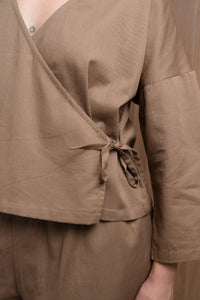 Brown wrap top with long sleeves and side tie, matching trousers, close-up view