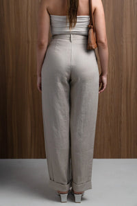 Back view of woman in high-waisted beige linen pants, white top, and brown purse