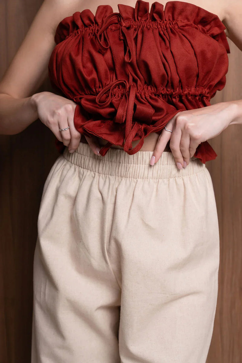 Woman wearing ruched red bandeau top and beige high-waisted pants with elastic waistband