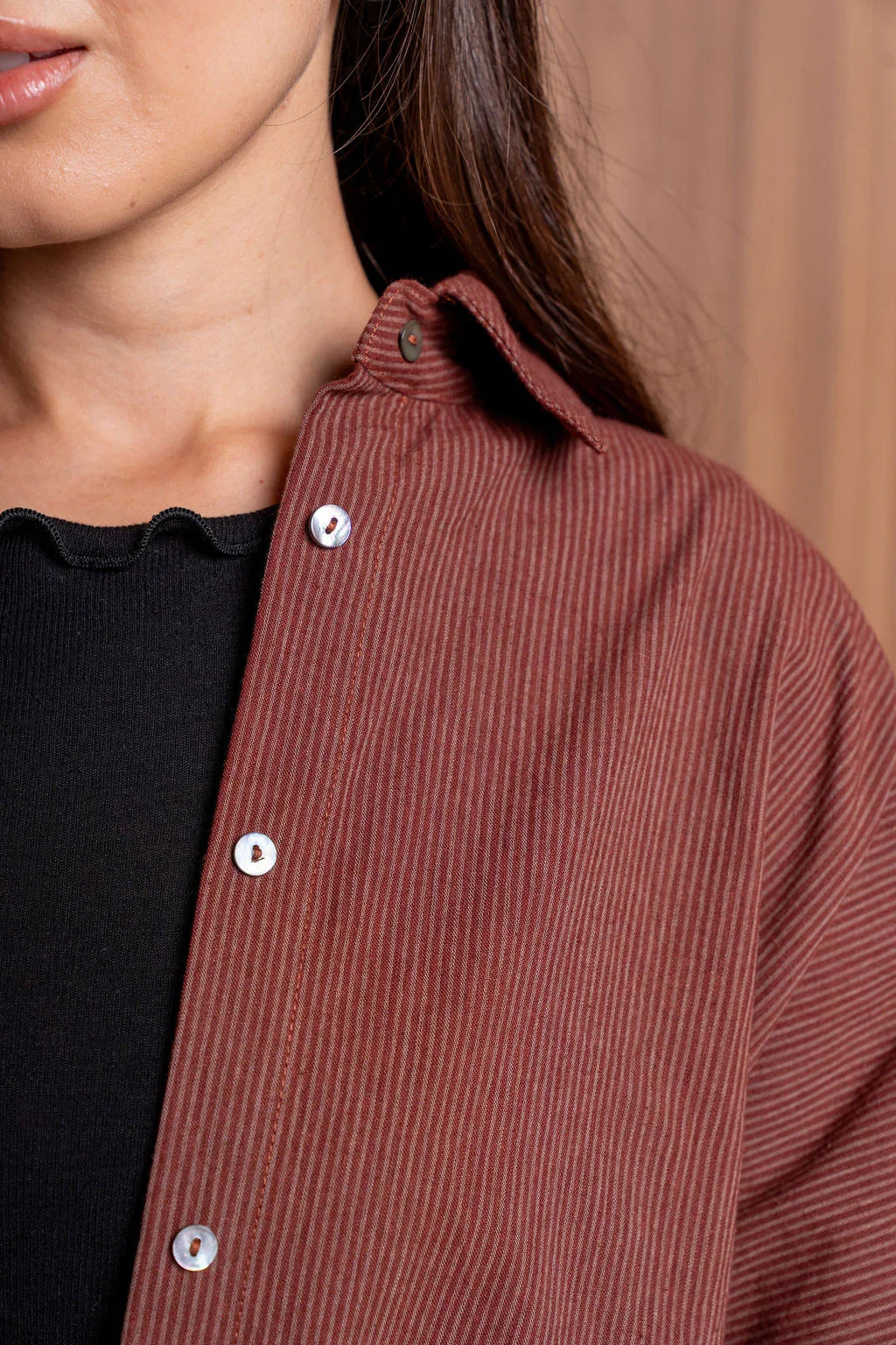 Close-up of woman wearing brown striped button-up shirt and black top