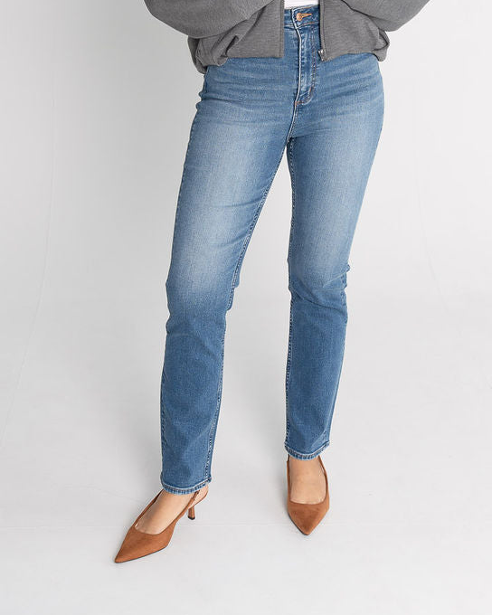 Woman wearing a gray sweater and blue jeans on a white background