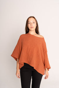Woman wearing a rust-colored poncho against a plain background
