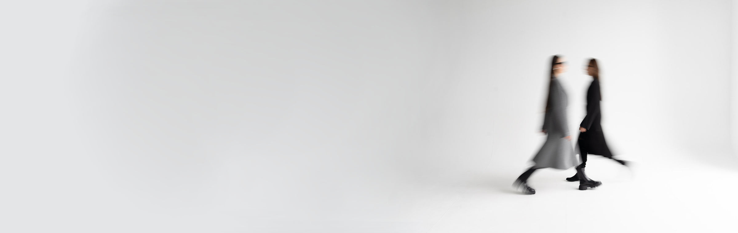 Two blurred figures walking on a white background