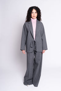 Woman wearing a gray pinstripe suit with a pink top on a white background