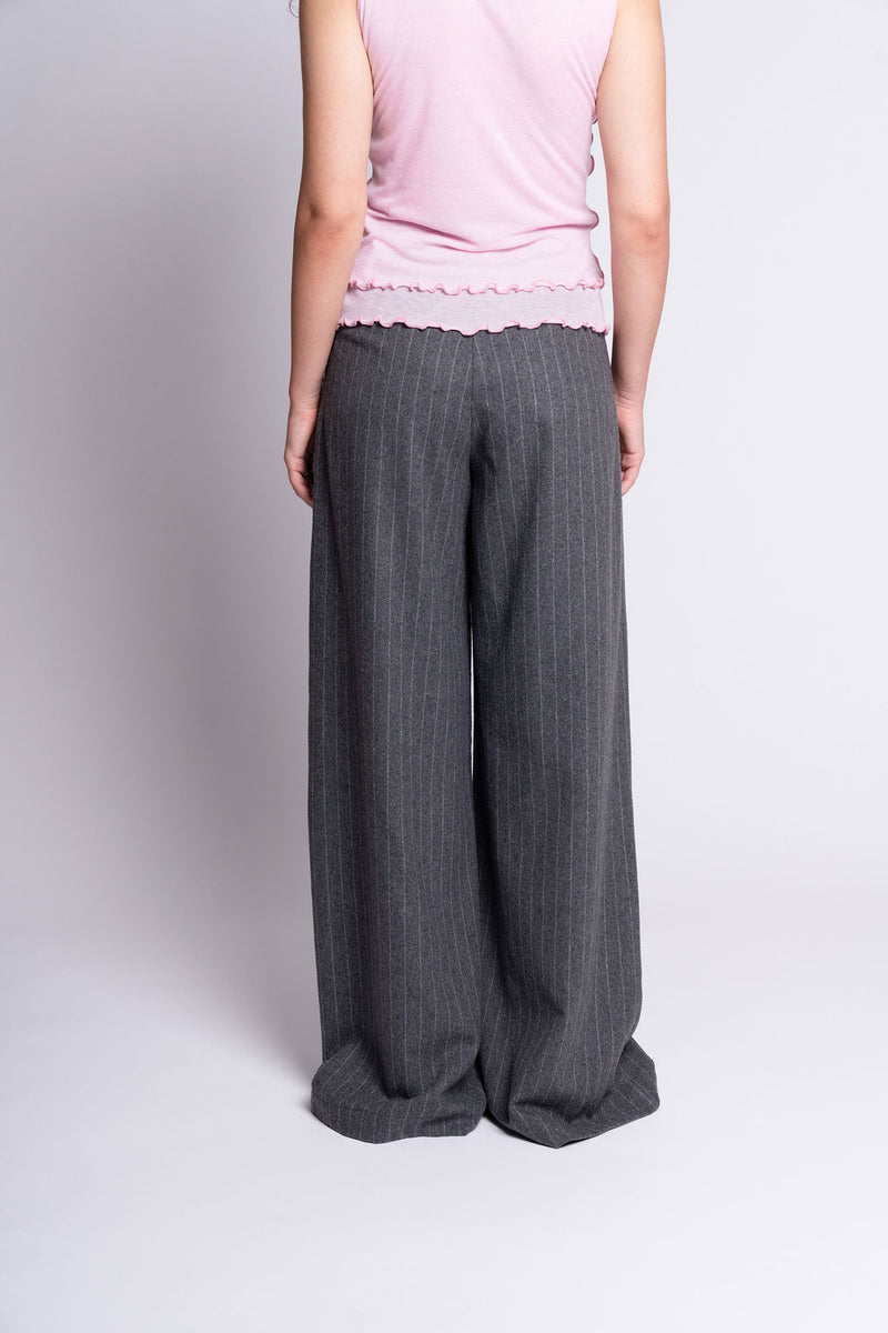 Person wearing gray wide-leg pants and a pink top on a white background