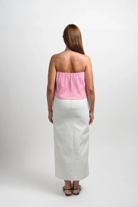 Woman in pink strapless top and white skirt, back view, studio fashion photo