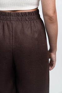 Close-up of brown high-waisted elastic pants and ribbed white crop top