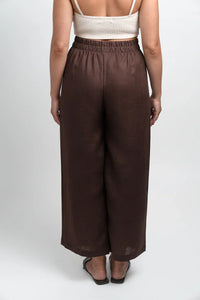 Back view of woman wearing brown wide-leg linen pants and white crop top