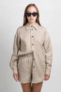 Woman in beige linen button-up shirt and shorts set with black cat-eye sunglasses