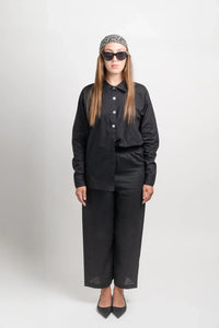 Woman in black button-up shirt and wide-leg pants with sunglasses and printed headscarf
