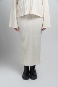 Ivory ribbed knit skirt and sweater set with black chunky boots on a light background