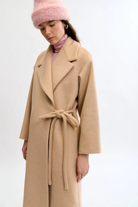 Woman wearing a beige coat and pink hat on a white background
